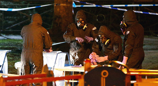 Members of the emergency services wearing protective clothing work